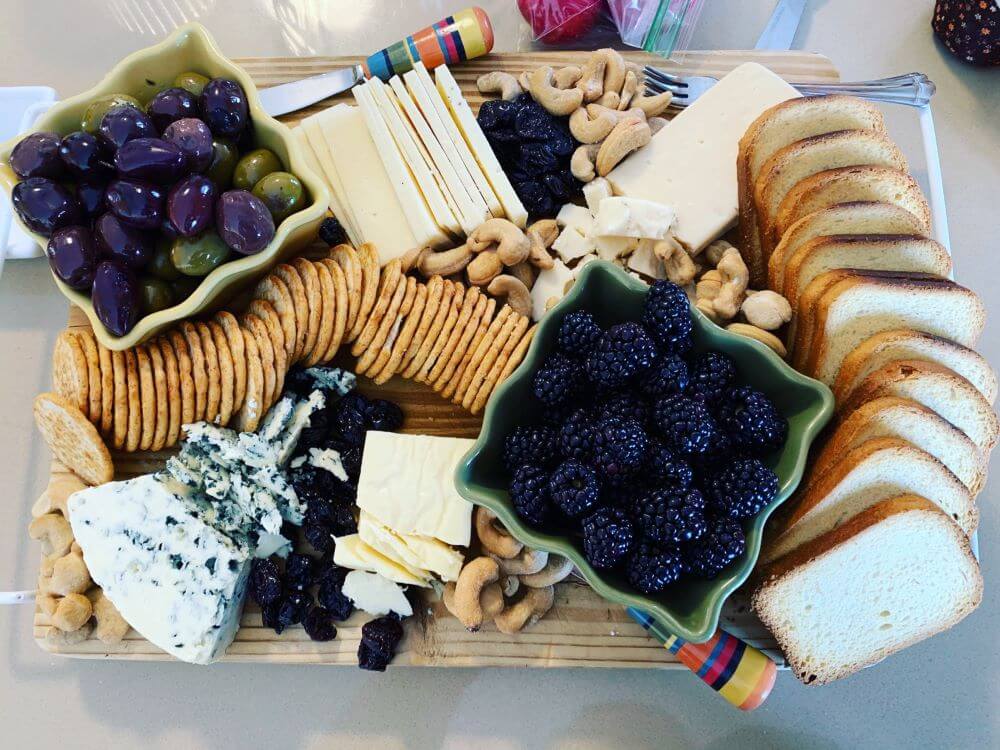 alt text = "charcuterie board with bread, crackers, a variety of cured meats, cheeses and accompaniments"