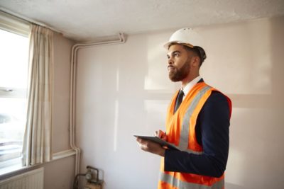 home inspector conducts four point inspection in hardhat and safety vest