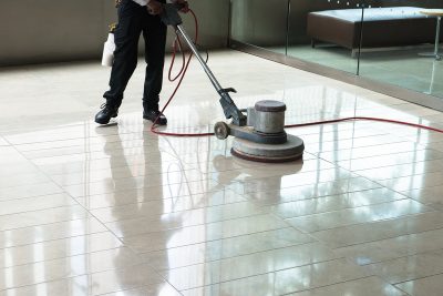 alt="Condo association maintenance depicted by a maintenace worker polishishing the floor in a condo lobby"