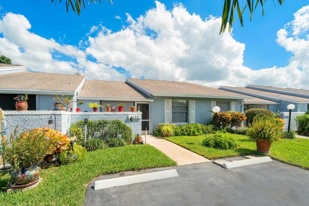 alt="Light blue attached villa with a green lawn in South Florida neighborhood"