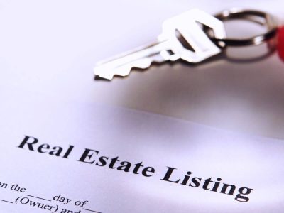 alt="Close up of a house key sitting on top of a Real Estate Listing Contract"