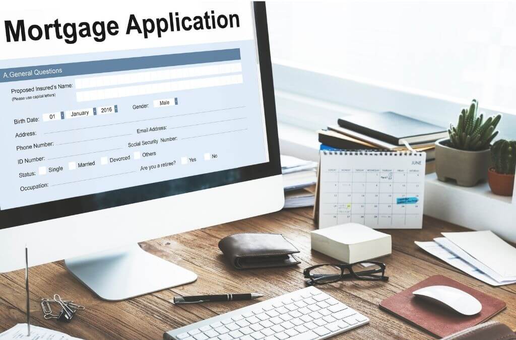 alt text = "a computer reading mortgage application sits on a wooden desk with common office supplies and two plants