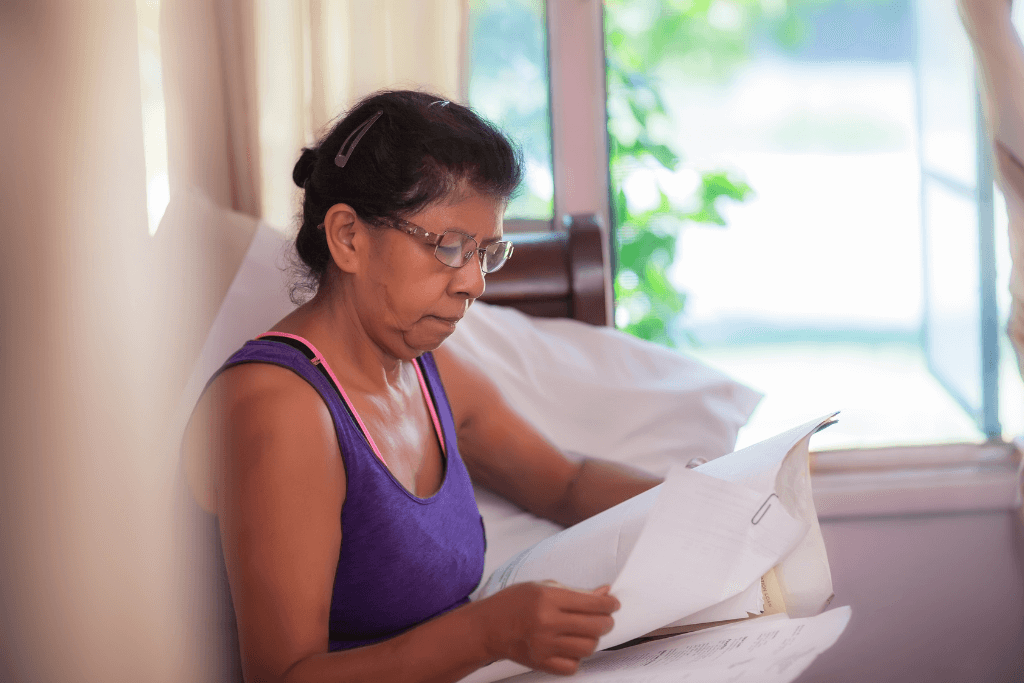 alt = "a 55+ woman reviews her loan paperwork to avoid mortgage relief scams"