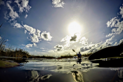 alt = "sun shines on a person kayaking on the horizon in may 2022 in south florida"