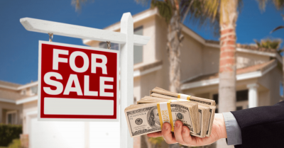 alt="Two story Florida home with a red for salke sign in the front yard behind a man holding stacks of cash.