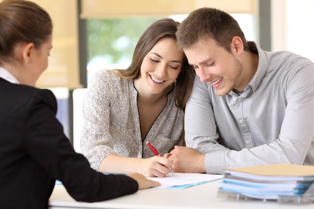 Homebuyer reviewing a purchase offer contract with a real estate agent before submitting an offer on a house